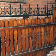 Забор деревянный с коваными элементами фотография